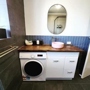 a bathroom with a washing machine and a mirror at Casa Luna Beachside Apartment in Henley Beach South +7 photos