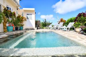 a swimming pool with chairs and a house at Casita in Rodrigues Island