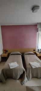 two beds in a room with a pink wall at Albergo Drena in Drena