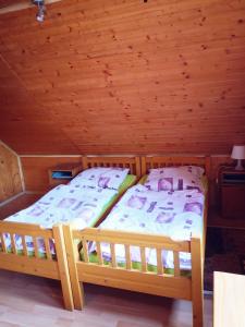 two beds in a room with a wooden ceiling at Chata TICHA in Oščadnica