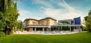 a large building with chairs in a yard at Villa Nicolli Romantic Spa Resort - Adults Only in Riva del Garda