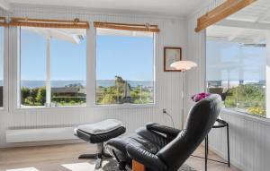 a living room with a chair and a lamp and windows at Fyrrehuset in Helnæs By