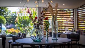 two vases with flowers on a table in a restaurant at Auberge Bressane de Buellas in Buellas