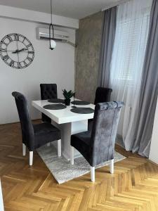 ニシュにあるApartment Aleksandrijaの黒い椅子と時計が付いた白いダイニングテーブル