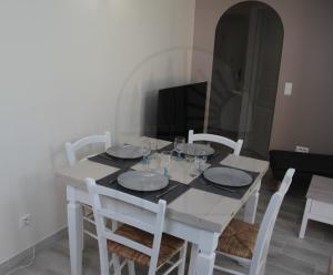 a white dining room table with white chairs and a television at L'Echappée Provençale - 4 Etoiles in Saint-Laurent-des-Arbres +22 photos