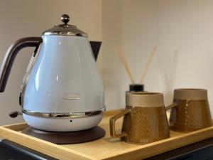 a tea kettle and two cups on a wooden tray at LANG Hotel GINZA 1K in Tokyo