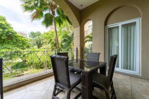 a balcony with a glass table and chairs on a porch at Matapalo 204- 2 Bedroom Condo At Tamarindo in Tamarindo