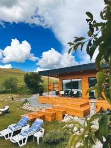 a house with a deck and chairs in front of it at Story Cabin Lake in Cîmpeneşti