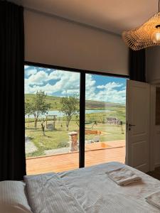 a bedroom with a bed and a large glass window at Story Cabin Lake in Cîmpeneşti