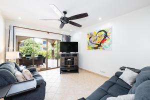 a living room with two couches and a flat screen tv at Sunrise 6- Ocean View 2 Br Condo, Steps To The Beach in Tamarindo
