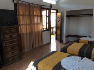 Cette chambre comprend deux lits et une télévision. dans l'établissement Posada Aguila Real, à Palenque