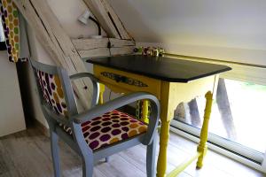 a yellow table and a chair next to a window at Le Lido in Sézanne