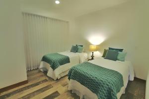 a bedroom with two beds with green and white sheets at Peninsula 25 in Tamarindo +32 photos