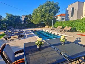 eine Terrasse mit Tisch und Stühlen und einem Pool in der Unterkunft Holiday Home Nino with amazing swimming pool in Slatine