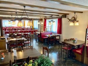 a restaurant with tables and chairs and red chairs at Hotel Waldhof in Bürglen