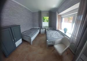 a room with two beds and a chair and a window at Lüttje Warfthuus in Krummhörn