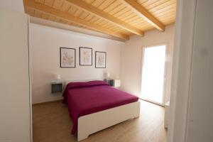 a white bedroom with a bed with a purple blanket at La casa nel verde in Recanati
