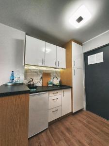 a kitchen with white cabinets and a black counter top at Apart & Plus in Okuninka