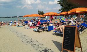 a crowd of people sitting on a beach with umbrellas at Apart & Plus in Okuninka