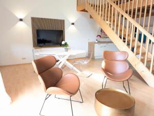 a living room with chairs and a table and a tv at Galeriewohnung bei Wasserburg am Inn in Soyen