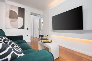a living room with a couch and a tv on a wall at Emerald Stone Apartment Varkiza in Vari