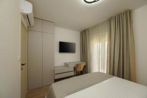 a bedroom with a bed and a desk and a television at Villa BILA in Podstrana
