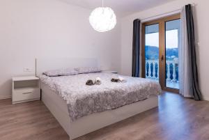 a white bedroom with a bed and a large window at Grgurić Apartments in Rab