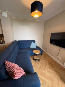 a living room with a blue couch and a flat screen tv at Apartament Diuna in Krynica Morska +30 photos