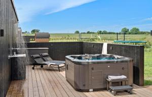 a hot tub on a deck with a table and a chair at Cozy Home In Børkop With Sauna in Børkop