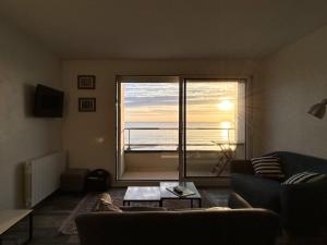 salon z kanapą i dużym oknem w obiekcie les cles de la mer w mieście Wimereux