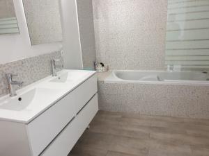 Un baño con dos lavabos y una bañera. en La maison de Nadège, en Lion-sur-Mer