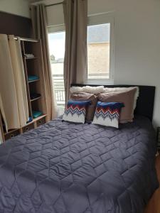 Un dormitorio con una cama con almohadas y una ventana. en La maison de Nadège, en Lion-sur-Mer