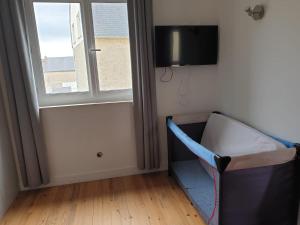 a baby crib in a room with a window at La maison de Nadège in Lion-sur-Mer