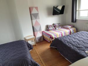 a bedroom with a bed and a couch and a tv at La maison de Nadège in Lion-sur-Mer