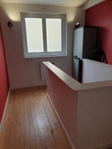 una cocina vacía con nevera y ventana en La maison de Nadège, en Lion-sur-Mer