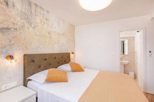 a bedroom with a bed with white sheets and orange pillows at SoHo apartment on the waterfront in Mlini
