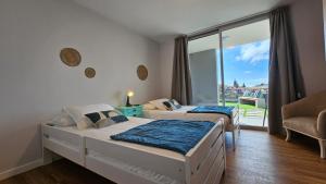 two beds in a room with a balcony at Magnólia Residence in Funchal