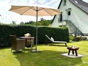 an umbrella and chairs and a table in a yard at Pures Wohlfühlen mit privater Sauna & Garten in Meschede