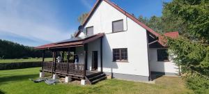 a white house with a porch on the grass at Karwica 39G Mazury jezioro Nidzkie in Karwica