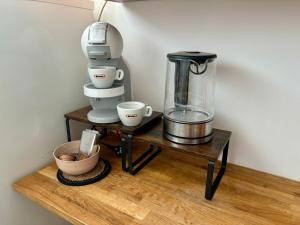 a coffee maker and cups on a wooden table at Apartament Różowy Jeleń in Gliwice