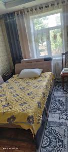 Ysyk-KölにあるGuest House Oimoのベッドルーム1室(黄色い毛布と窓付)