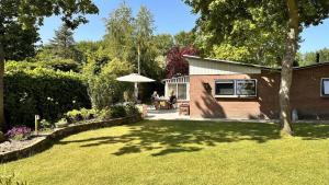 a yard with a house and a table and an umbrella at Bosje 1 - Ouddorp NOT INTENDED FOR COMPANY OR WORK-RELATED STAYS in Ouddorp