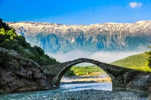 a bridge over a river with a mountain in the background at Joan Guesthouse in Përmet