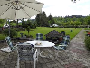 a patio with a table and chairs and an umbrella at Agroturystyka Pod Jesionami in Lądek-Zdrój