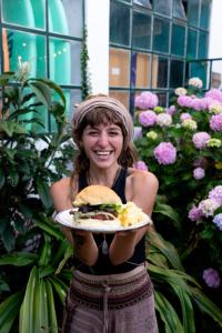 a woman holding a plate with a sandwich on it at Natural Mystic Hostel in Costa da Caparica