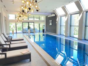a large swimming pool with chairs and a chandelier at Hotel Burabay in Shchūchīnsk