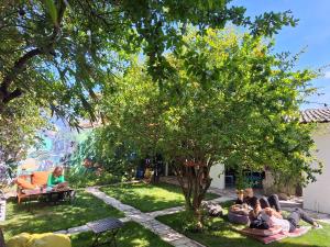 a group of people sitting in the grass under a tree at Natural Mystic Hostel in Costa da Caparica