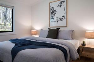 una camera da letto con un letto con lenzuola blu e una finestra di Bodhi Daylesford a Daylesford