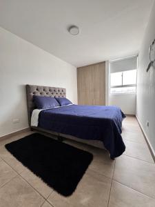 a bedroom with a bed with blue sheets and a rug at MIRADOR DE CASTILLA - Sector CENTRAL in Manizales