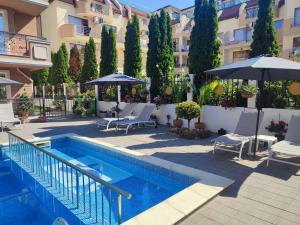 a swimming pool with chairs and umbrellas next to a building at Divela 3 Apartments in Nesebar